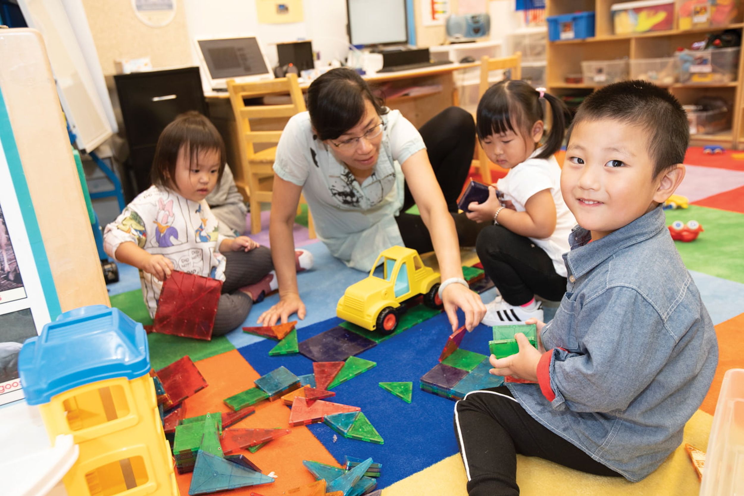 Small children play with a teacher in a classroom